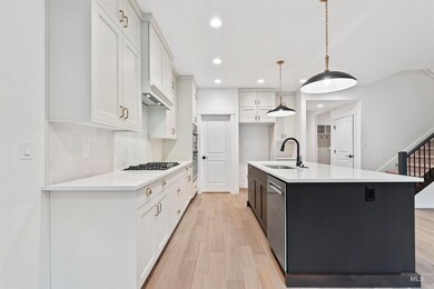 Kitchen featuring light wood-style flooring, white cabinetry, pendant lighting, recessed lighting, and a center island with sink