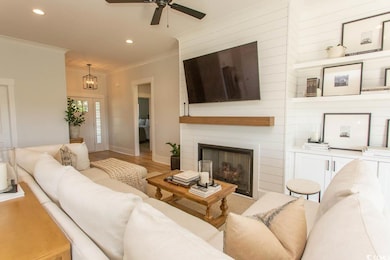 Living area with crown molding, ceiling fan, recessed lighting, light wood-style flooring, and a large fireplace