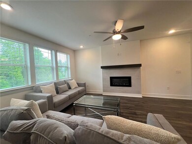 Living room with wood finished floors, a ceiling fan, a tile fireplace, and recessed lighting