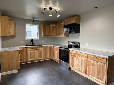 Kitchen with stainless steel range with electric cooktop, light countertops, and black microwave
