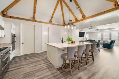 Kitchen with white cabinets, pendant lighting, light stone counters, a kitchen breakfast bar, and stainless steel range