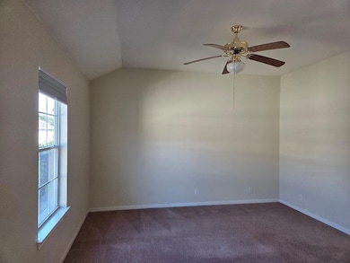 Unfurnished room with dark carpet, ceiling fan, and vaulted ceiling