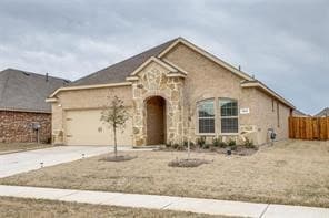 View of front of home featuring driveway, stone siding, and an attached garage