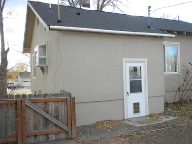 View of property exterior featuring a shingled roof, stucco siding, and a gate