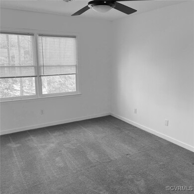 Spare room featuring ceiling fan and dark carpet