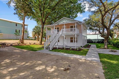 View of front of property featuring covered porch, stairway, and a front lawn