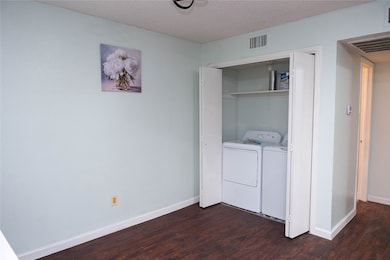 Washroom featuring dark wood-type flooring, a textured ceiling, and washing machine and dryer