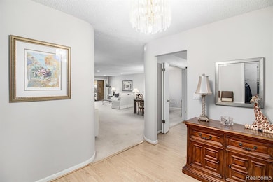 Hallway featuring a textured ceiling, light wood-style floors, and a chandelier