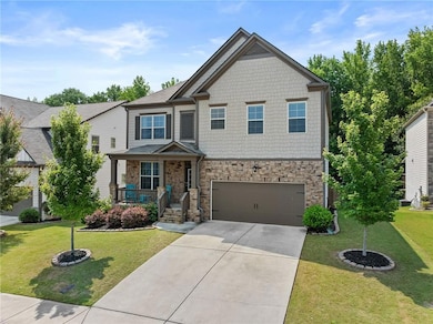 Craftsman inspired home featuring stone siding, a porch, an attached garage, concrete driveway, and a front lawn
