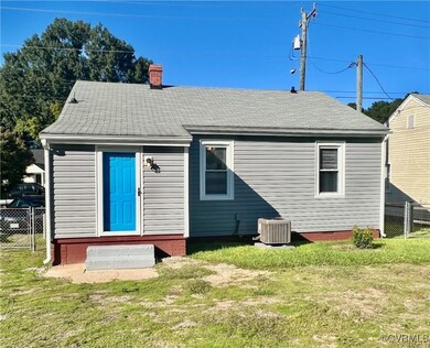 Rear view of property with cooling unit and a lawn