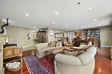 The living room boasts an airy ambiance with elegant wood flooring, seamlessly connected to the dining space and a stylish kitchen counter bar, perfect for modern living and entertaining.