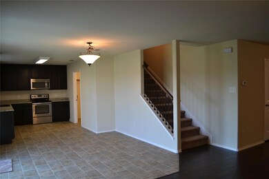 Kitchen with appliances with stainless steel finishes, hanging light fixtures, light tile flooring, and light stone countertops