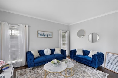Living area featuring crown molding, plenty of natural light, and wood finished floors