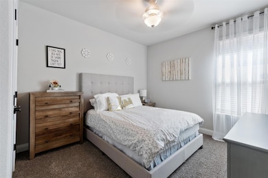 Carpeted bedroom featuring ceiling fan and baseboa