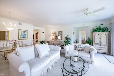 Living area featuring light colored carpet, a chandelier, and a ceiling fan