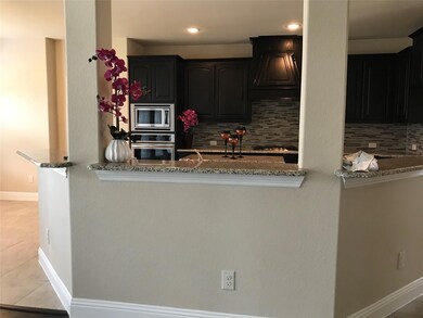 Kitchen featuring stone counters, stainless steel appliances, decorative backsplash, custom exhaust hood, and light tile patterned flooring