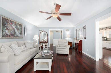 Living room featuring ceiling fan, dark wood-style flooring, and a raised ceiling