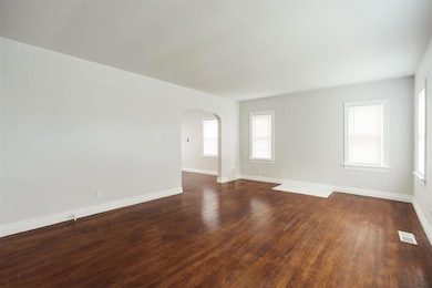 Unfurnished room featuring arched walkways and dark wood-style flooring