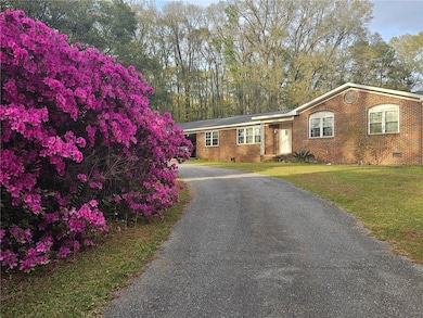 View of front facade with crawl space, brick siding, a front lawn, and driveway