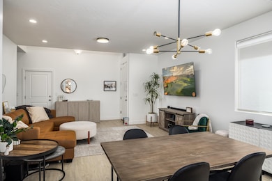 Dining area with light wood finished floors, a chandelier, and recessed lighting