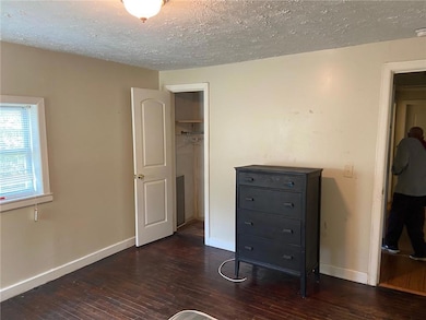 Unfurnished bedroom featuring wood-type flooring, a closet, baseboards, and a textured ceiling