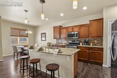 Kitchen featuring a sink, appliances with stainless steel finishes, light stone countertops, dark wood-type flooring, and backsplash