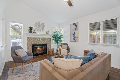 Living room featuring vaulted ceiling, ceiling fa