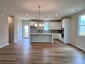 Kitchen with dark wood-style floors, white cabinetry, hanging light fixtures, and recessed lighting