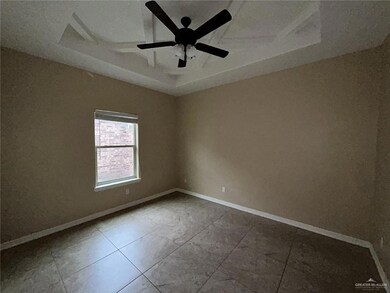 Spare room with a tray ceiling, a ceiling fan, and baseboards