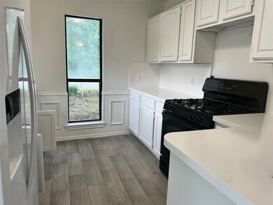 Kitchen with gas range oven, stainless steel fridge with ice dispenser, hardwood / wood-style flooring, and white cabinetry