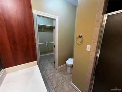 Bathroom featuring toilet, tile patterned flooring, a spacious closet, and a shower stall