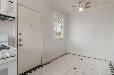 Foyer with light tile patterned floors, ornamental molding, and ceiling fan