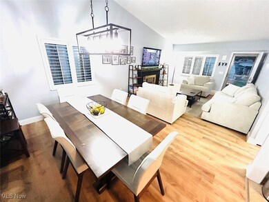 Dining room featuring wood finished floors, a glass covered fireplace, and vaulted ceiling