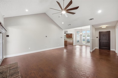 Unfurnished living room featuring high vaulted ceiling, dark wood-style floors, ceiling fan, a chandelier, and recessed lighting