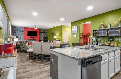 Kitchen featuring stainless steel dishwasher, a sink, an accent wall, white cabinets, and ceiling fan