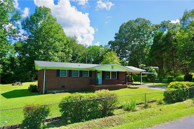 Ranch-style home featuring covered porch, crawl space, brick siding, a carport, and a fenced front yard