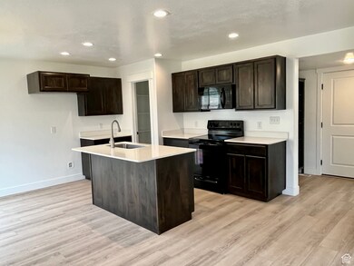 Kitchen featuring black appliances, a sink, baseboards, light wood-type flooring, and recessed lighting