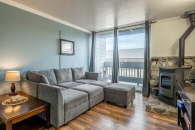 Living room featuring wood finished floors, a wood stove, ornamental molding, and floor to ceiling windows