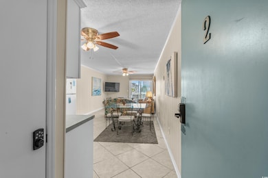 Dining space with light tile patterned floors, a ceiling fan, and a textured ceiling