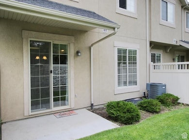 Doorway to property featuring a patio, a shingled roof, and stucco siding