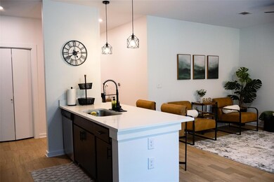 Kitchen featuring a breakfast bar area, hanging light fixtures, a peninsula, light wood-style floors, and light stone countertops