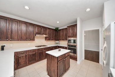 The kitchen features tile flooring and recessed li