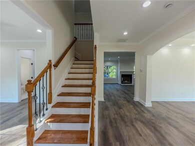 Stairs featuring wood finished floors, arched walkways, ornamental molding, recessed lighting, and a fireplace