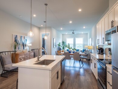 Kitchen with white cabinetry, open floor plan, stainless steel appliances, backsplash, and an island with sink