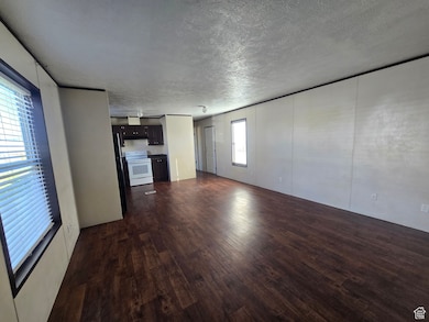 Unfurnished living room with dark wood-type flooring and a textured ceiling