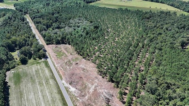 Aerial view of property and surrounding area featuring a forest and rural landscape