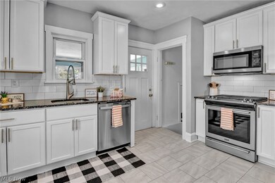 Kitchen featuring sink, dark stone counters, backsplash, and stainless steel appliances