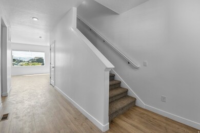 Stairs with a textured ceiling and wood finished floors
