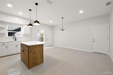 Kitchen featuring a sink, visible vents, white cabinets, light countertops, and a center island