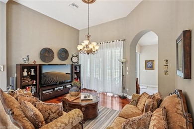 Living room featuring wood finished floors, a chandelier, arched walkways, and a towering ceiling
